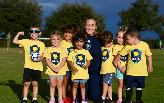 sol sc kids playing soccer in a group yellow sol sports club shirt